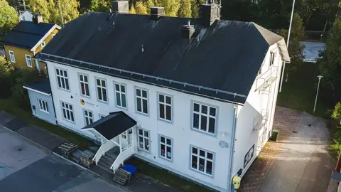 Gamla Engelmarks-huset i Jokkmokk med vit fasad och tre våningar. Fotad utifrån en sommarkväll. Foto: CJ Utsi