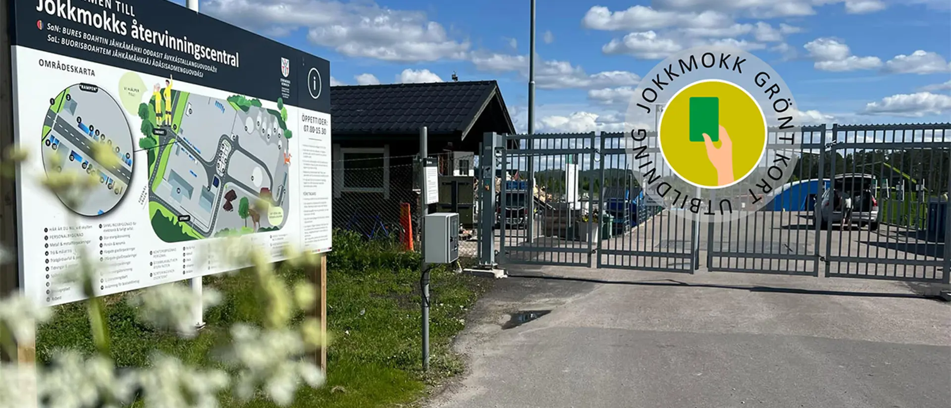 Jokkmokks återvinningscentrals entré med en översiktskarta till vänster och stänga grindar. En sommardag med blå himmel. Foto.