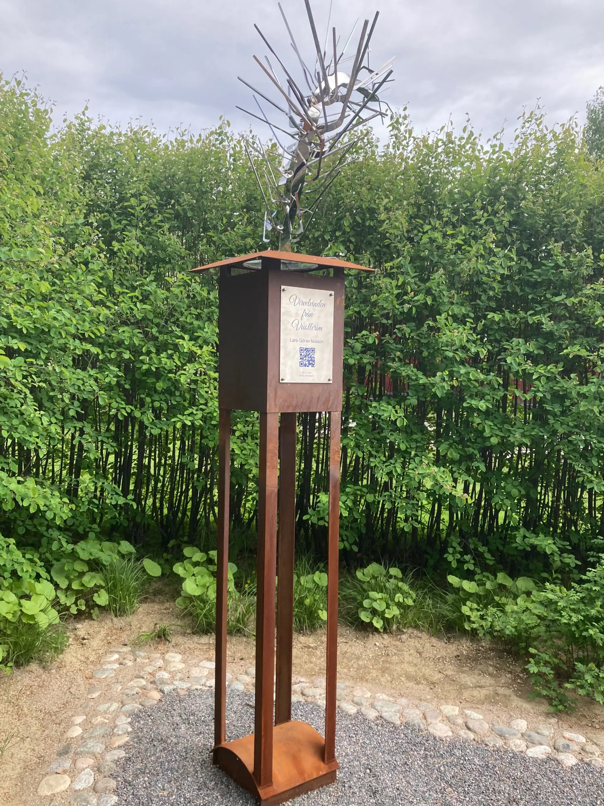 Statyn Vivelvinden i en grönskande parkmiljö en sommardag. Foto.