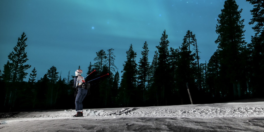 Foto av en man som åker längdskidor under norrsken