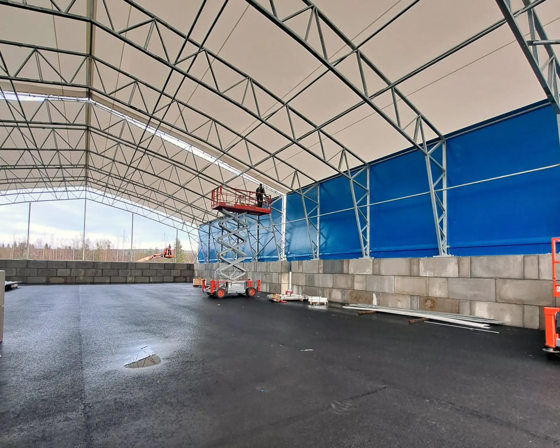 Inifrån omlastningstationen. Här ser man betongsargen, stålkonstruktionen, den blå tältduken och en stor asfalterad yta. Foto.