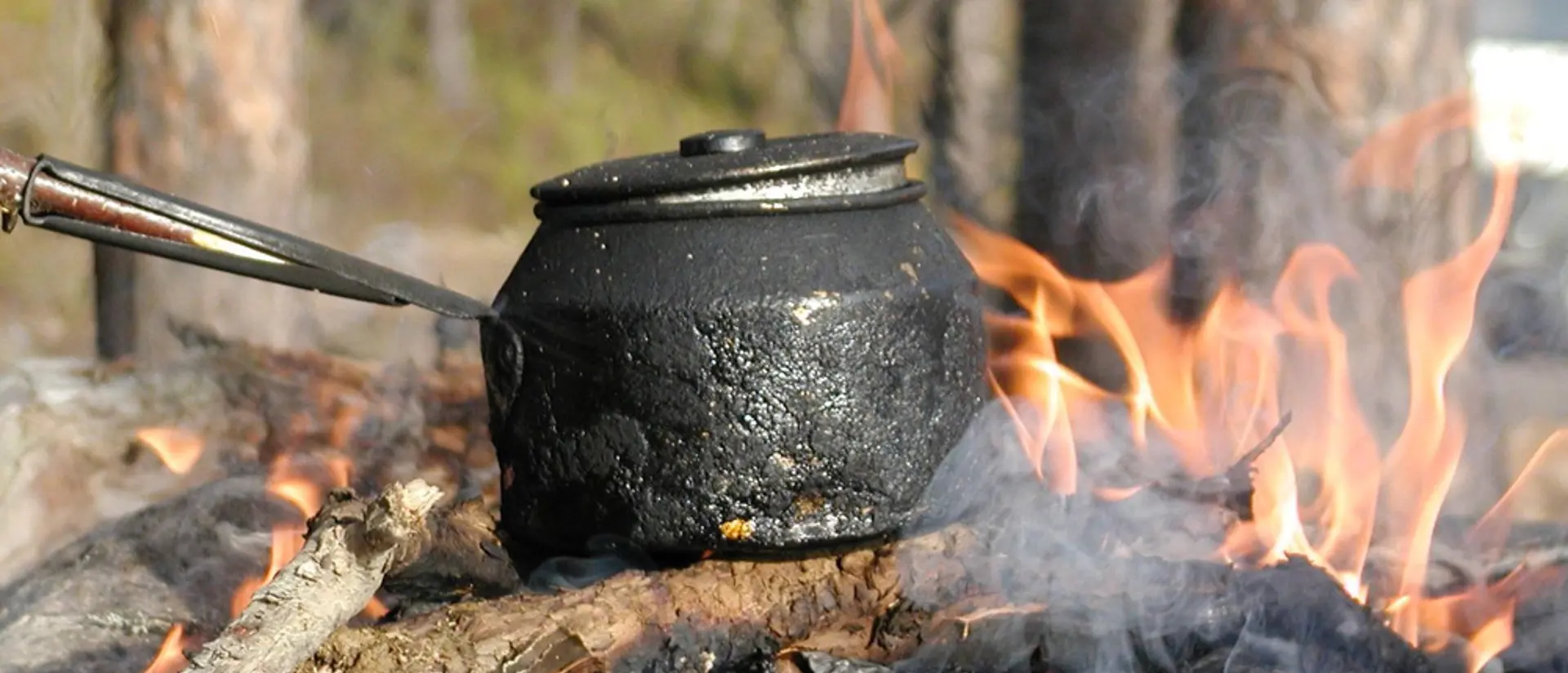 An outdoor fire with a coffee pan heating.