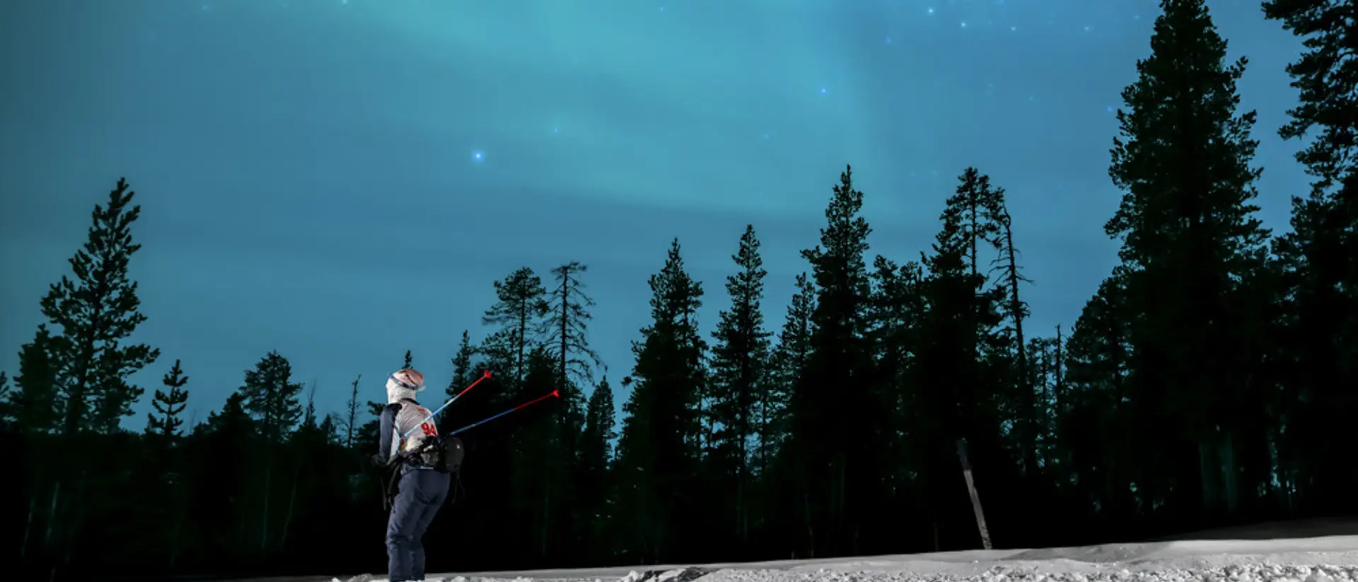 Foto av en man som åker längdskidor under norrsken